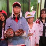 Cuatro jóvenes disfrazados posan con una serpiente en el Día de Muertos en el Zoológico de Nuevo Laredo