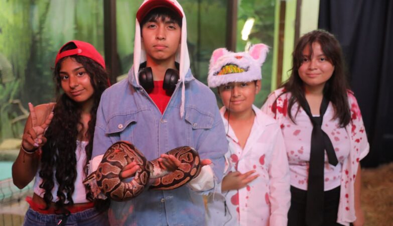 Cuatro jóvenes disfrazados posan con una serpiente en el Día de Muertos en el Zoológico de Nuevo Laredo